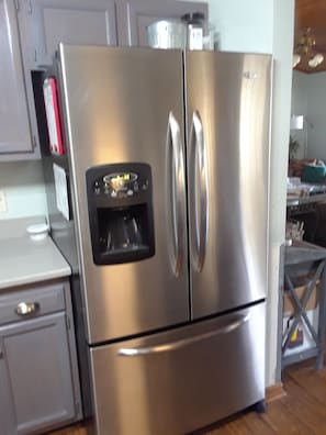 A stainless steel refrigerator with a built-in ice maker, a small drawer, and a freezer compartment.