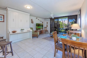 A spacious living area with a kitchen, dining table, and a large sliding glass door leading to an outdoor patio.