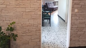A room with a stone wall, a potted plant, and a view into another room with a bed and a plant. - Holiday home Luma (with terrace and garden) (Egerkingen)