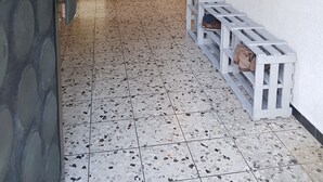 A hallway with a speckled tile floor, a white bench with shoes, and a wall-mounted rack with clothes. - Holiday home Luma (with terrace and garden) (Egerkingen)