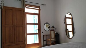 A bedroom with a wooden wardrobe, a desk with a chair, a mirror, and a bed. - La Casita de Ainhoa (Agüimes)  (Agüimes)
