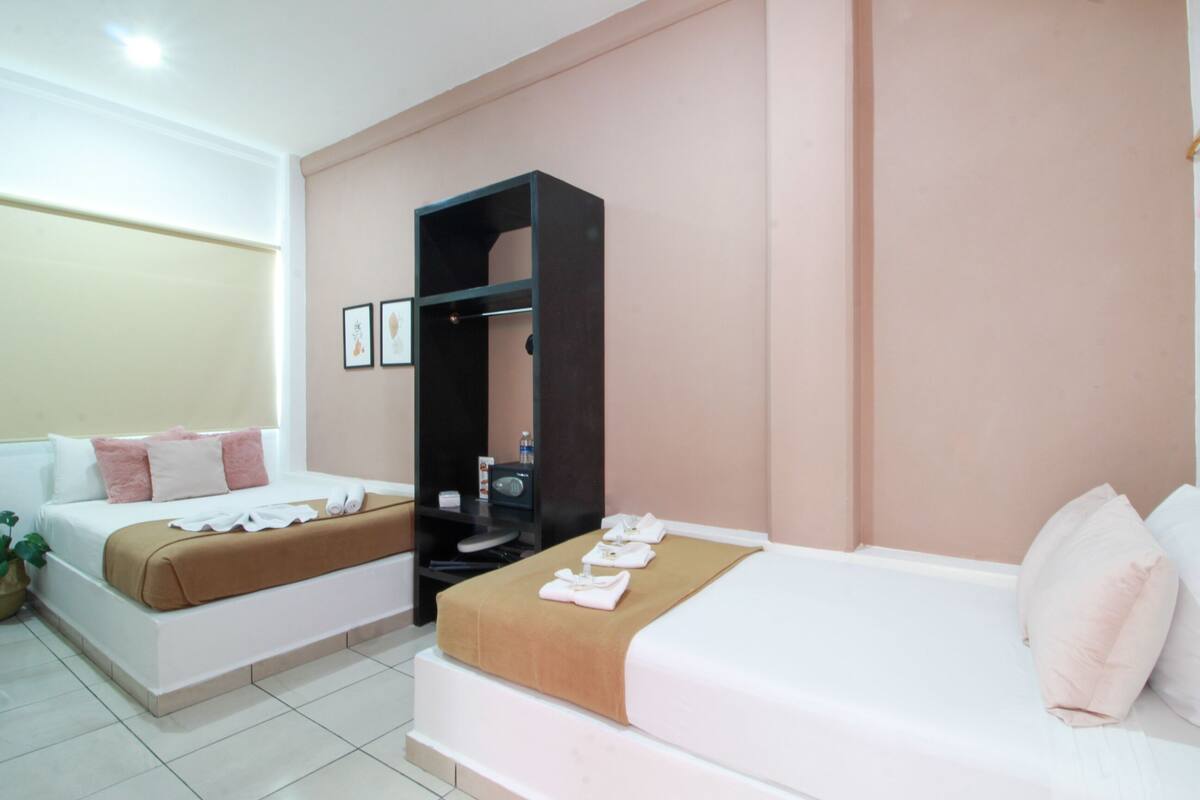 A hotel room with two beds, a wardrobe, and a small seating area.