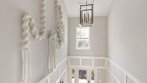 Una escalera con barandilla blanca, un candelabro y una ventana con vistas al exterior.