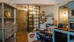A kitchen with a wooden cabinet, a sink, a stove, and copper pots on the wall.