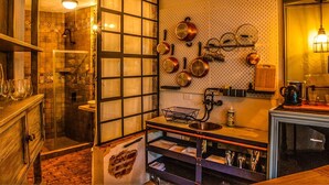 A kitchen with a wooden countertop, hanging pots, and a brick wall.