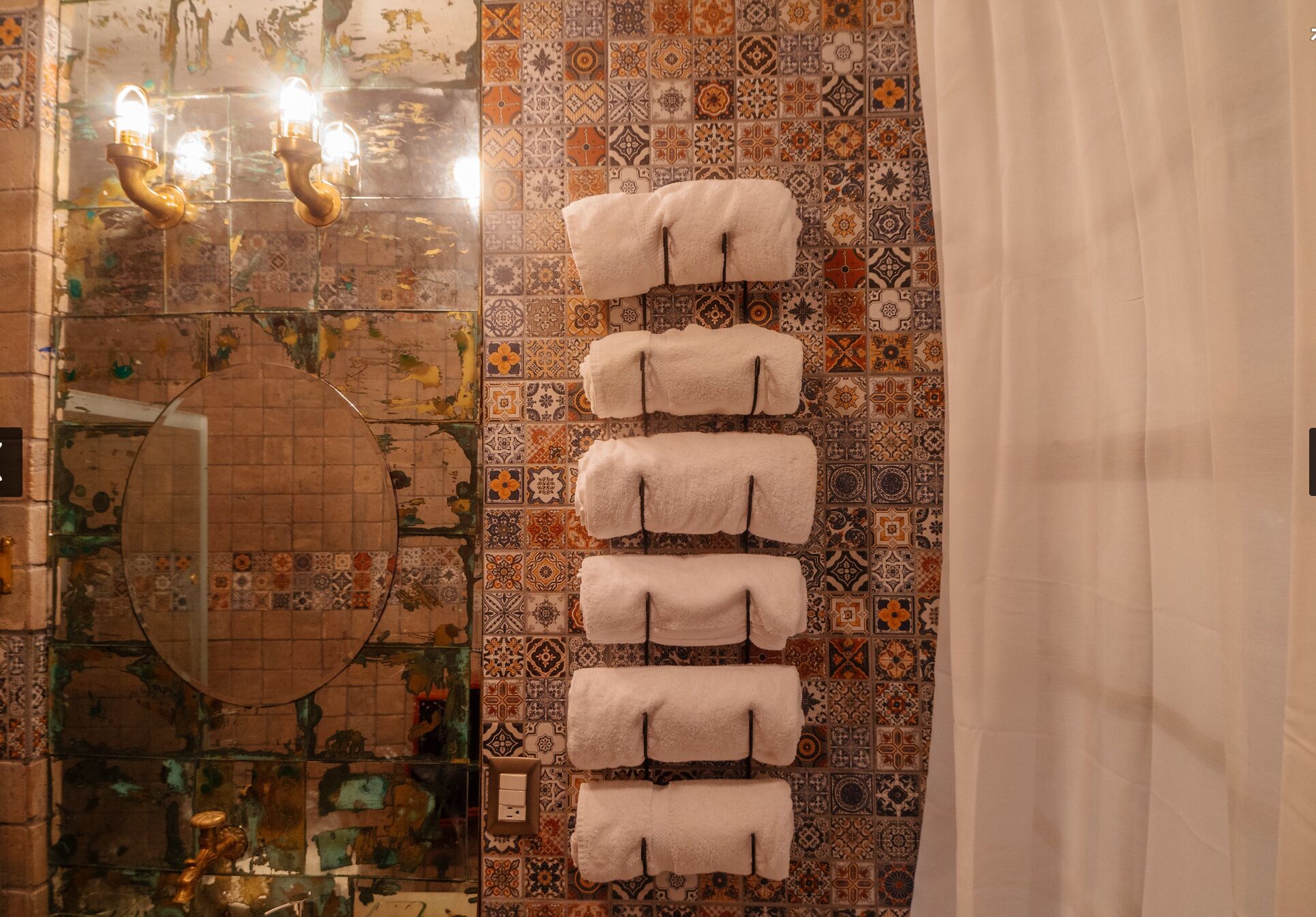 Ein Badezimmer mit gemusterten Fliesen, einem Spiegel und Handtüchern an einem Haken.