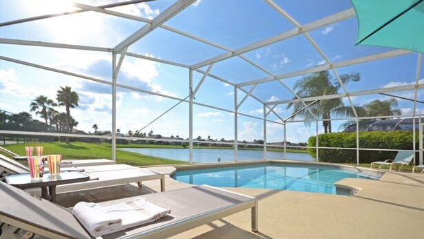 An indoor swimming pool with lounge chairs and a view of a golf course.