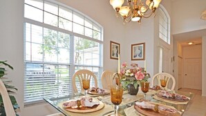 A dining area with a glass table, white chairs, and a chandelier.