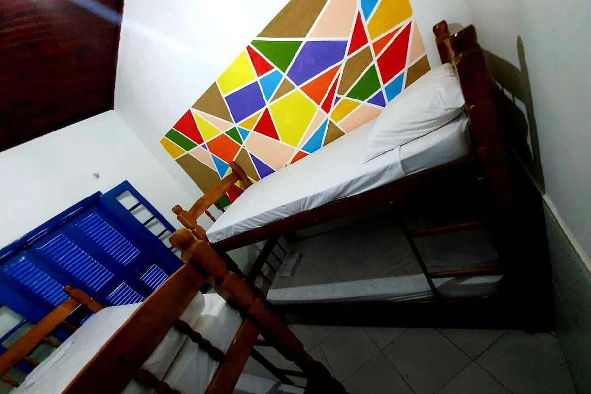 Un lit superposé avec une tête de lit aux motifs géométriques colorés et une tête de lit bleue sur le lit du bas.