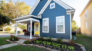 Una casa de dos plantas con fachada azul, un porche y un jardín cuidado.