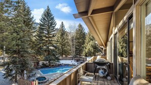 A deck with a pool, outdoor chairs, and a grill.