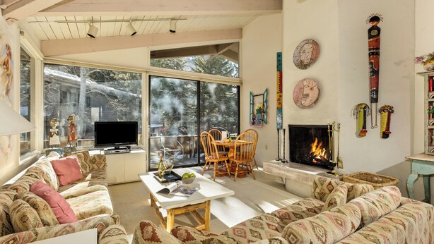 A spacious living room with a large window, a fireplace, and a television.