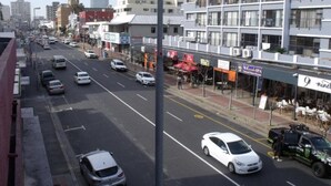 Een meerlaags hotel met een modern ontwerp, gelegen aan een drukke straat met zichtbare reclame voor verschillende bedrijven.