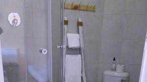 Een badkamer met een douchecabine van glas, een toilet en een handdoekrek.