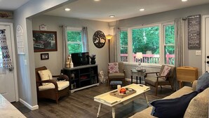 A spacious living room with a large window, a television, and a cozy seating area.