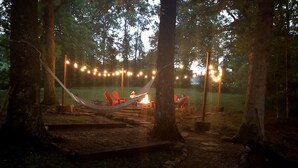 A campsite with hammocks, a fire pit, and string lights.