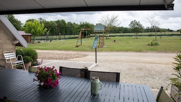 Relax on the patio with a view of the playground, complete with a table, chairs, and a potted plant.
