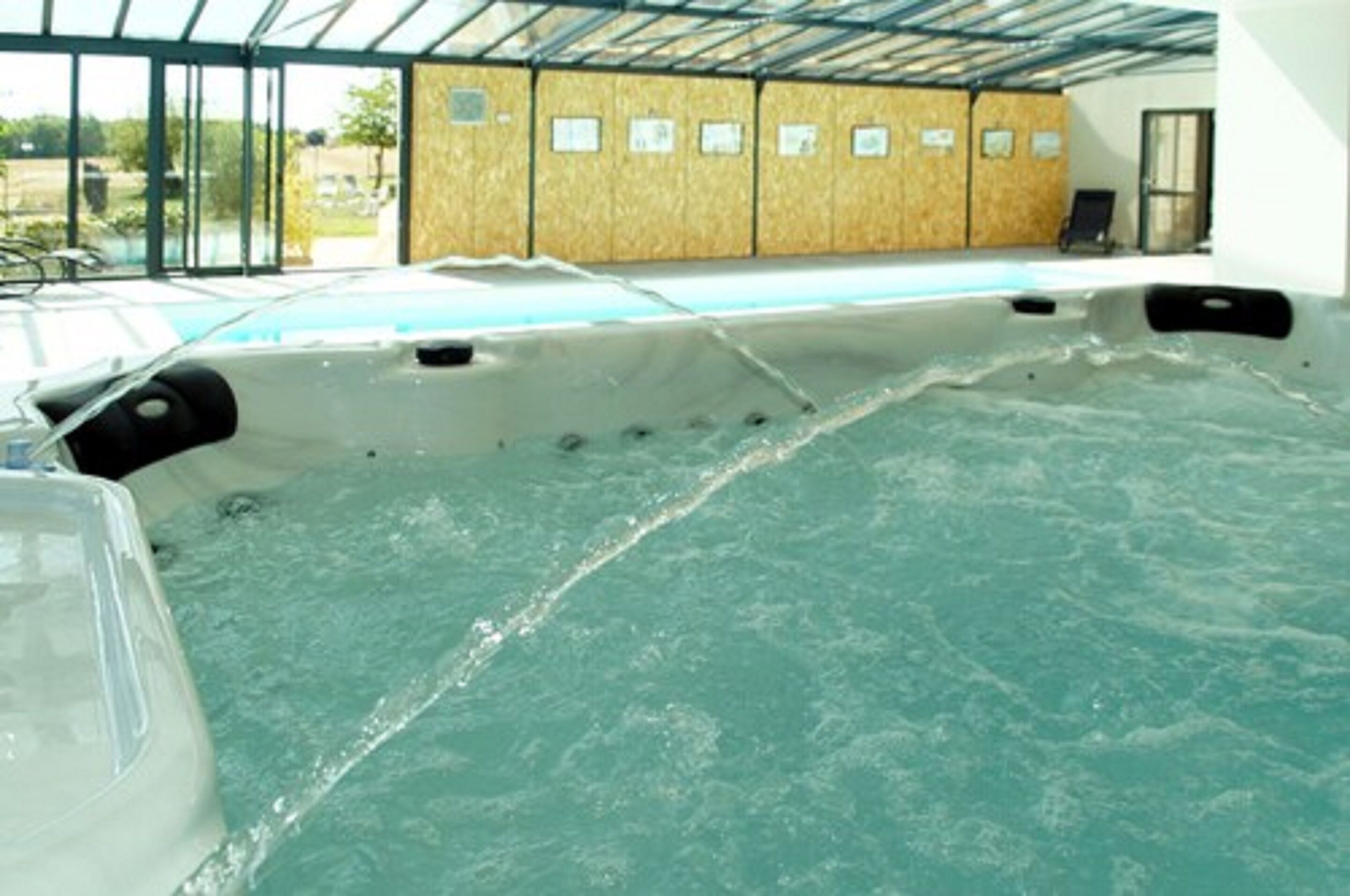 Un bain à remous doté d’une paroi en bois et d’une enceinte en verre.