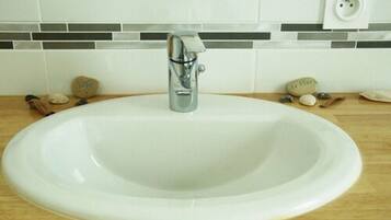 A white ceramic sink with a modern faucet, set against a tiled backsplash with a gray and white pattern.