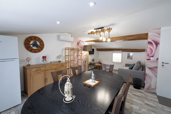 A modern kitchen with a wooden dining table, a clock, and a chandelier. - Best Saintonge (Port-d'Envaux)