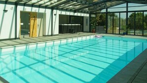 A swimming pool with a glass ceiling, surrounded by a covered deck area. - Best Saintonge (Port-d'Envaux)