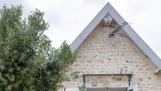 A stone building with a sloped roof, a window with white shutters, and a small table with chairs outside. - Best Saintonge (Port-d'Envaux)