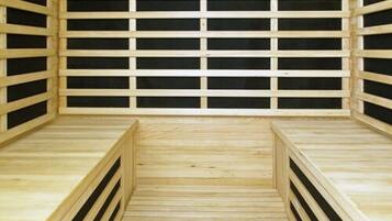 Una sauna de madera con una hilera de bancos y suelo de madera.