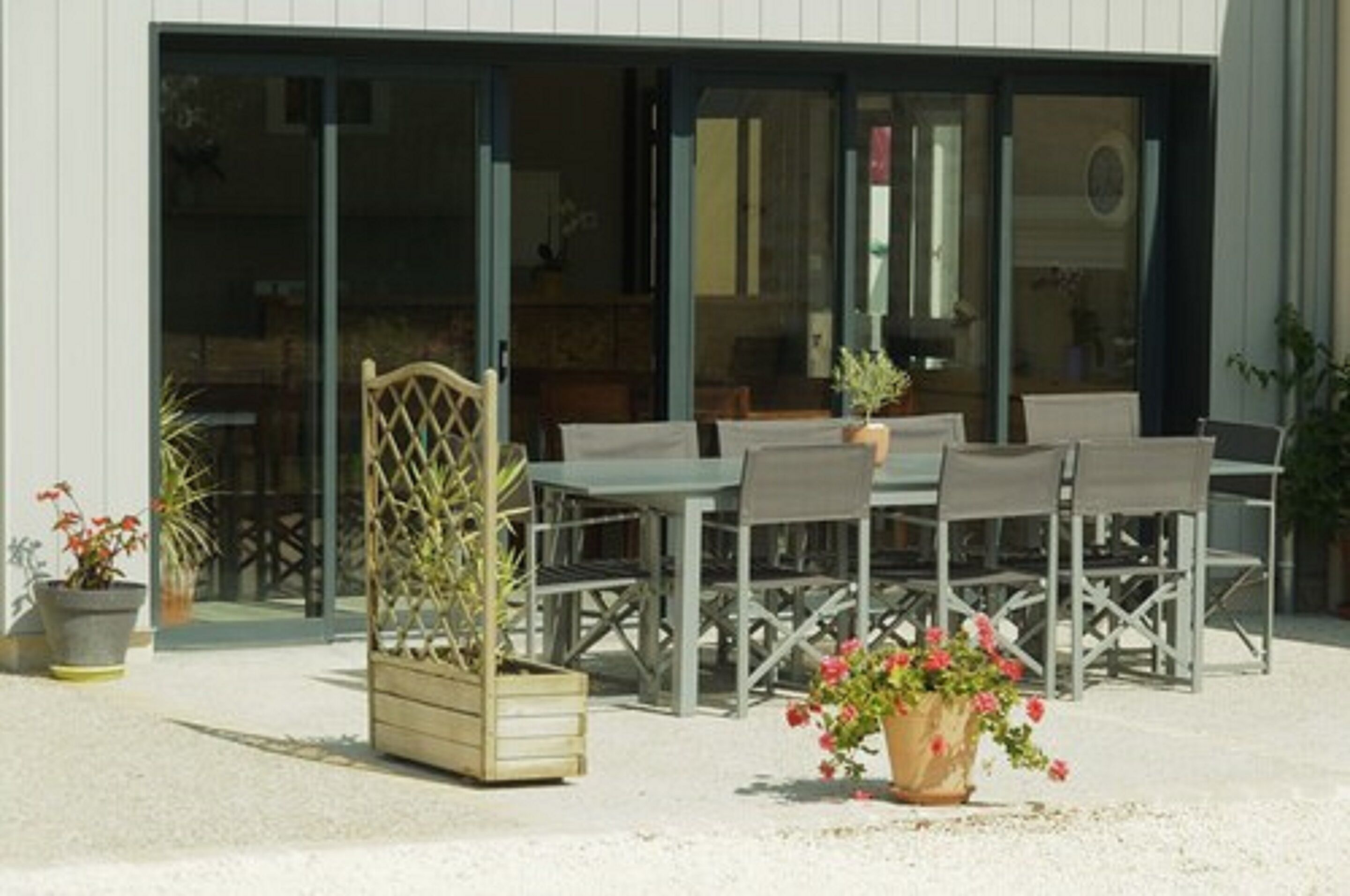 Ein Sitzbereich im Freien mit Tisch und Stühlen, umgeben von Topfpflanzen.