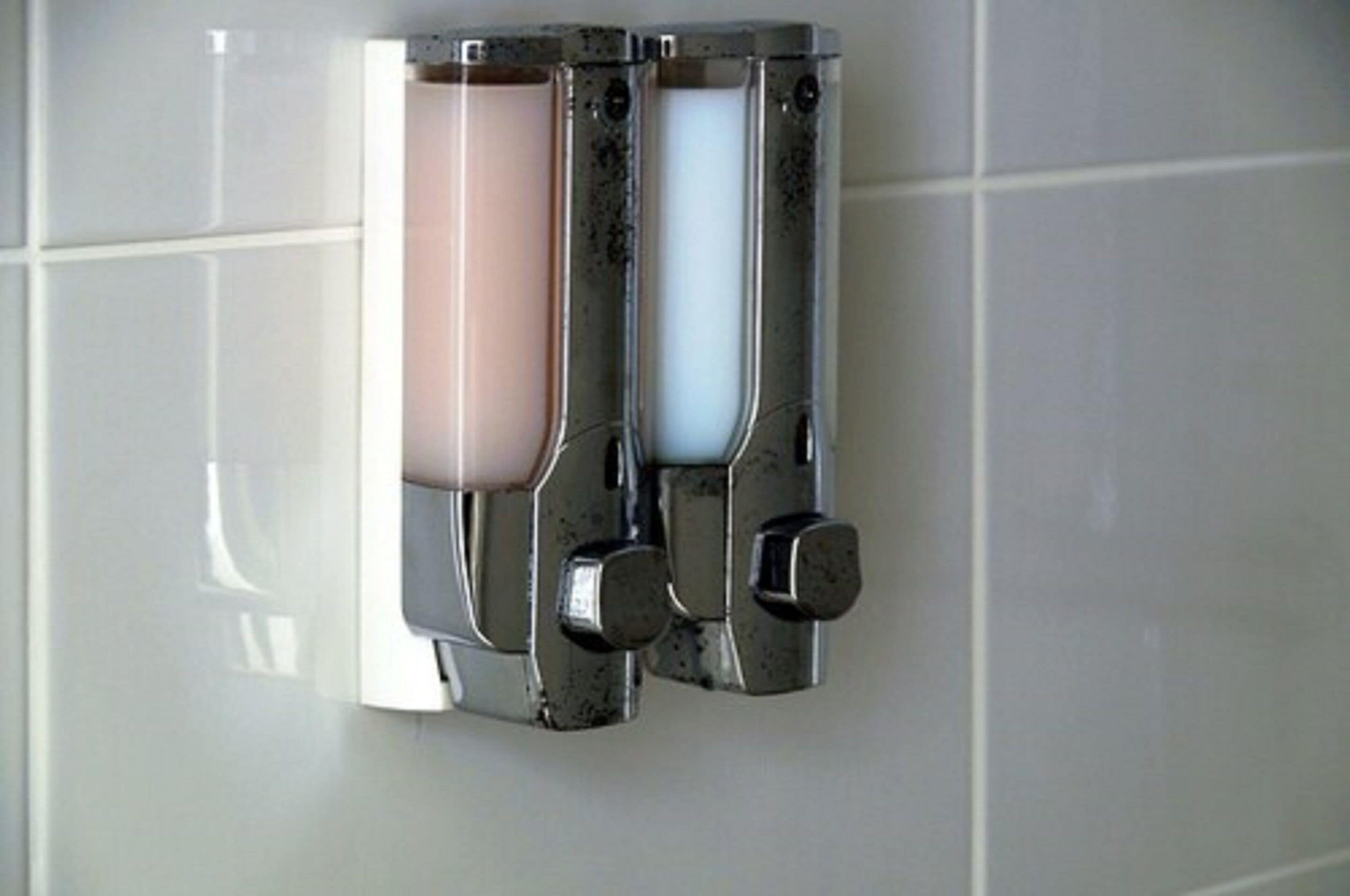 A wall-mounted soap dispenser with three compartments.