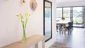 A modern dining area with a large window, a dining table with chairs, and a mirror on the wall. - Piper—Family Retreat in the Heart of Wine Country (Wilyabrup)