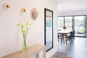 A modern dining area with a large window, a dining table with chairs, and a mirror on the wall.