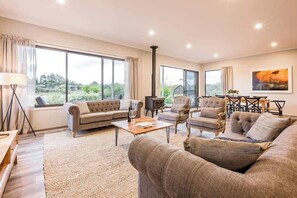 A spacious living room with a sofa, armchairs, a coffee table, and a fireplace.