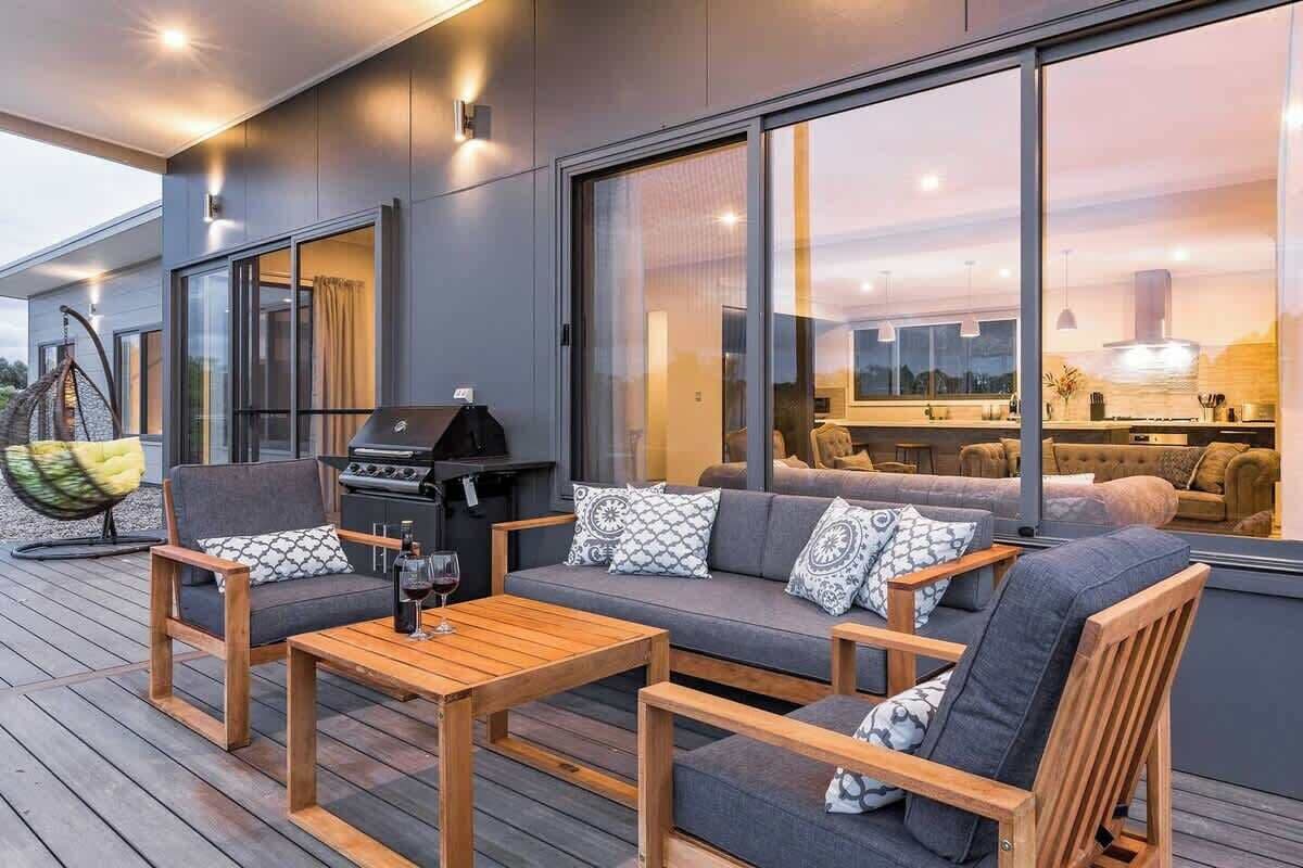 A modern outdoor living area with a sofa, chairs, and a grill.