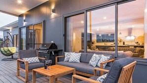 A modern outdoor living area with a sofa, chairs, and a grill. - Piper—Family Retreat in the Heart of Wine Country (Wilyabrup)