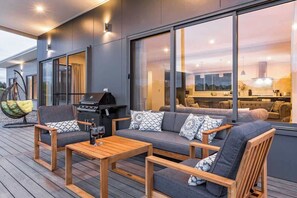 A modern outdoor living area with a sofa, chairs, and a grill.