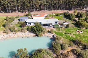 A large house with a swimming pool, surrounded by trees and a small garden.