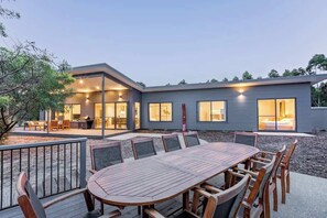 A modern house with a patio, a dining area with a table and chairs, and a visible kitchen area.