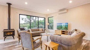 Una sala de estar moderna con chimenea, un conjunto de sofás, un televisor y ventanas grandes.