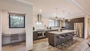 Una cocina moderna con una isla central, taburetes de bar y vistas al exterior.
