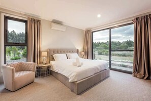 Une chambre moderne avec un grand lit, un canapé et une vue sur l’extérieur.
