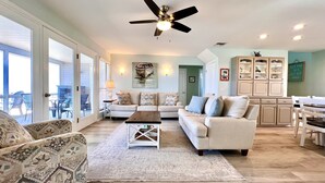 A spacious living room with a ceiling fan, a sofa set, a coffee table, and a dining area with a cabinet.