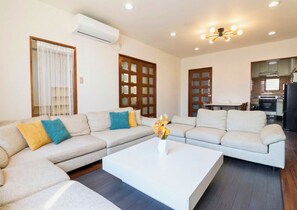 A modern living room with a sectional sofa, a coffee table, and a kitchen in the background.