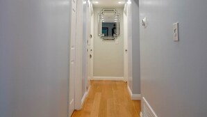 A hallway with wooden flooring, white walls, and recessed ceiling lights. - Adorable House with fireplace in backyard (Santa Clarita)