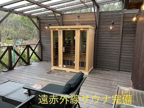 Une terrasse en bois avec un sauna, une porte vitrée et un banc.