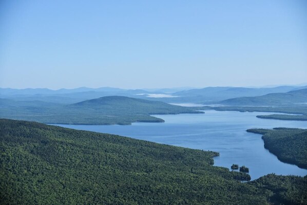 A coastal landscape with a large body of water surrounded by forested hills.