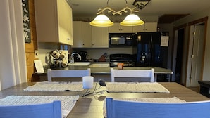 Un comedor con una mesa de madera, cuatro sillas y dos lámparas colgantes.
