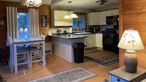 Interior acogedor de una cabaña con comedor, cocina y una pequeña sala de estar.