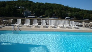 Ein klares Schwimmbecken mit weißen Liegestühlen und einer Holzterrasse.