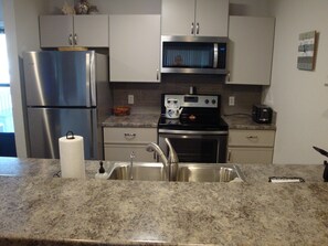 Enjoy cooking in this well-equipped kitchen with a refrigerator, microwave, and stove, along with a sink and faucet.