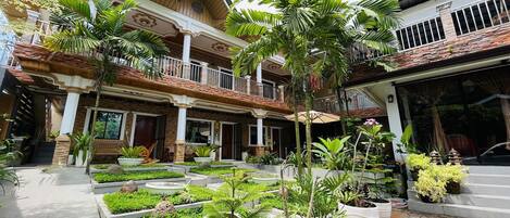 A multi-story building with a courtyard garden, balconies, and a covered entrance.